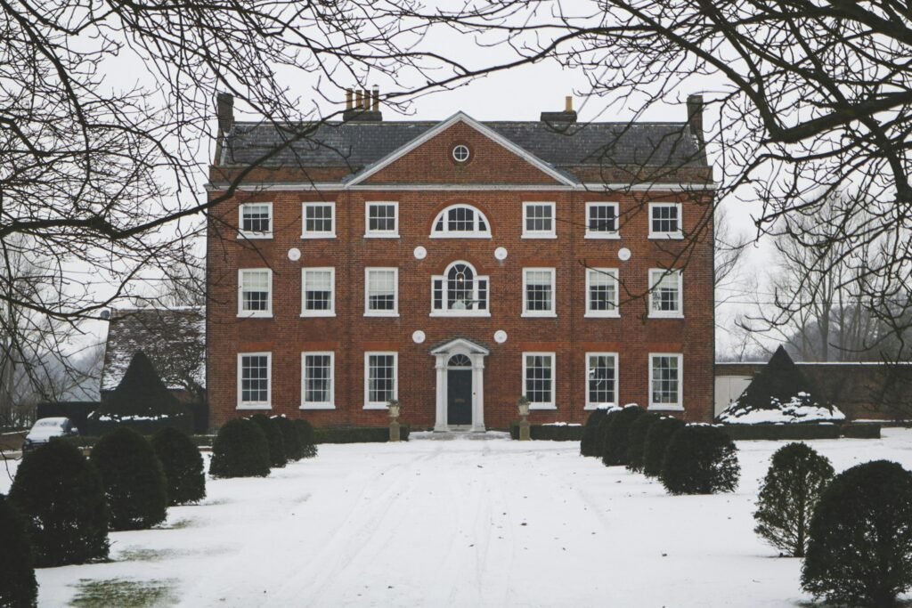 Elegant brick mansion set in a snowy winter scene with classic architectural details and stately symmetry.